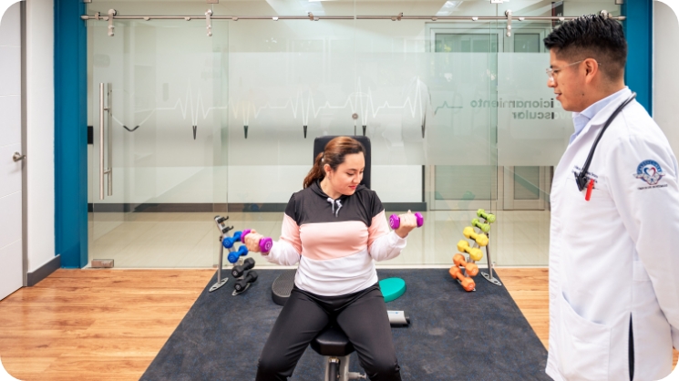 Cardiólogo en sala de rehabilitación acompañando a paciente haciendo ejercicio